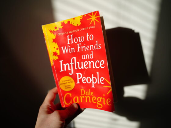 A hand holding the book How to Win Friends and Influence People by Dale Carnegie, a best book to read for self-development