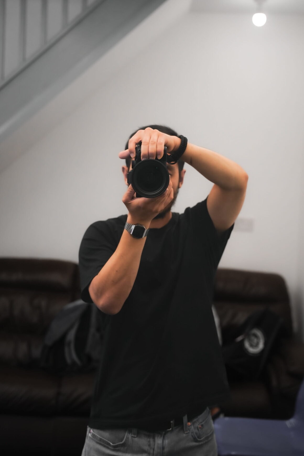 Person taking photographs with a camera indoors as one of the productive hobbies for active millennial men.