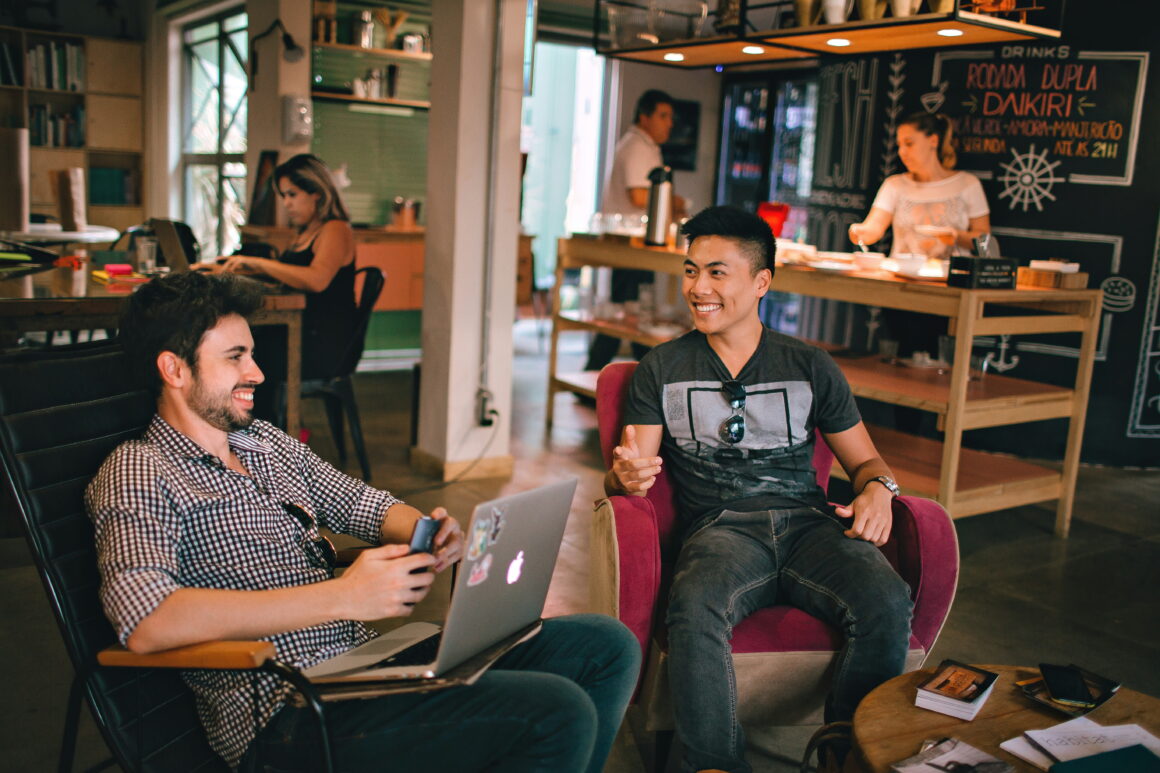 Two people having a casual conversation in a café, representing productive social hobbies for active millennial men. 